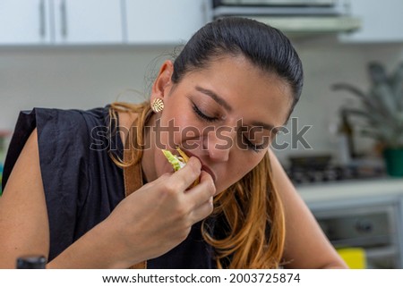 young woman eating a freshly prepared taco in the kitchen