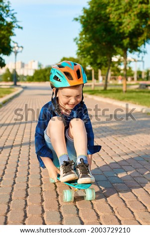 Little red-haired boy rides a skateboard in the park in the summer