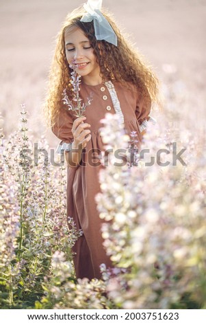 Girl in a field with flowers. Summer evening, little girl close-up in nature. High quality photo