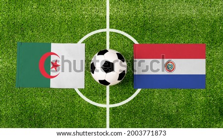 Top view soccer ball with Algeria vs. Paraguay flags match on green football field.