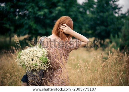 redhead woman of forty years with a large bouquet of wildflowers in summer in nature