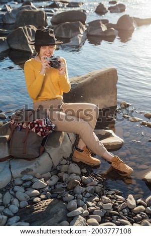 Young woman traveler is taking pictures of nature on retro camera