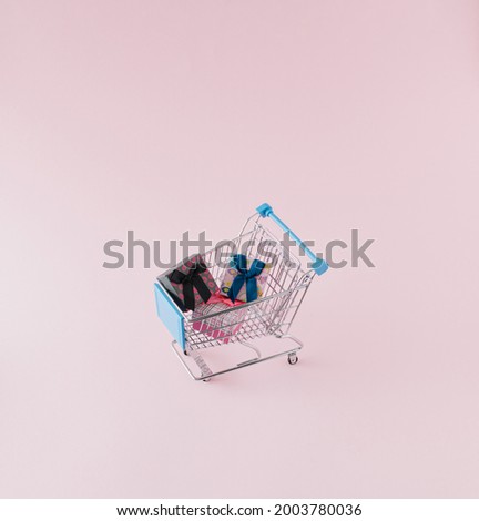 Shopping cart with presents on pink pastel background. Minimal concept.