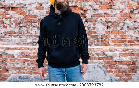 City portrait of handsome guy wearing black blank hoodie and baseball cap with space for your logo or design. Mockup for print