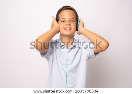 Cute smiling boy listen to the music with headphones and thumbs up isolated over white background.