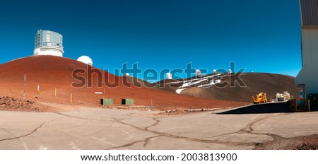 Low angle view Keck Observatories on top of Mauna Kea mountain peak on Big Island of Hawaii, United States with deep blue sky and volcanic landscape. Ultra-wide high resolution panoramic photo.