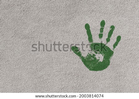 Green handprint on a house facade