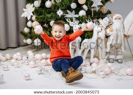 little boy playing with christmas balls on the background of a christmas tree