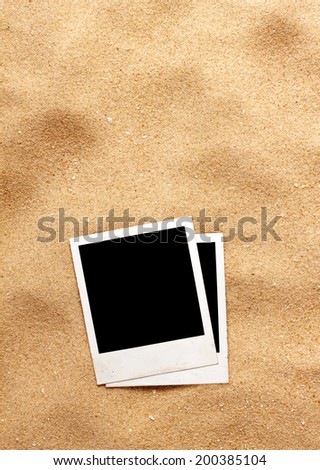Old style empty photo cards lying on a sea sand. Sunny summer background 