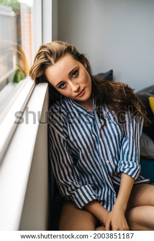 positive beautiful young woman sitting in bed looking to camera