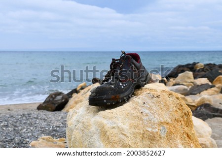 Summer sea beach blue sky old black used man boot red thread seashells macro background 