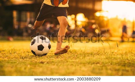Action sport scene of a group of kids having fun playing soccer football for exercise in community rural area under the twilight sunset. Picture with copy space.