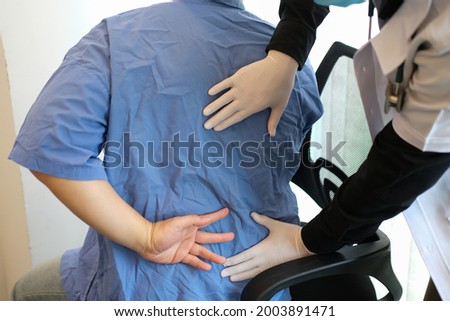 Closed up with a patient show area feeling pain at lower back and physiotherapy assessment around patient's back.