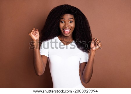 Photo of young black girl happy positive smile rejoice victory fists hands lucky isolated over brown color background