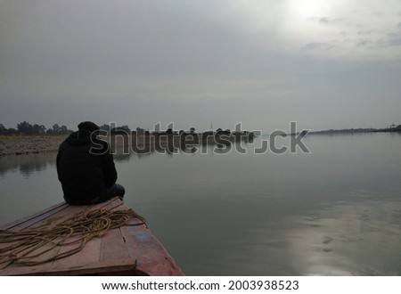 silhouette of a man sitting on a boat in a river, blurry shot
