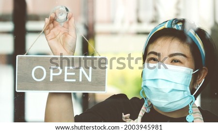 Coffee shop asian woman owner with face mask, open after lockdown quarantine.