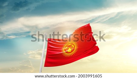 Kyrgyzstan national flag waving in beautiful clouds.