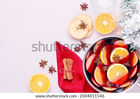 Cooking mulled wine with oranges, apples, anise and cinnamon for Christmas on pink table top, top view, flat lay, copy space