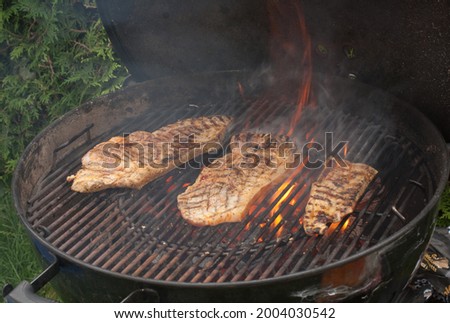 grilling a steak on a charcoal grill in summer