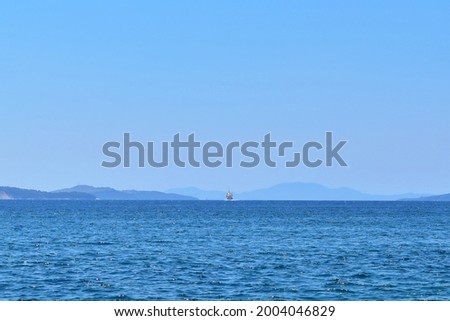 Seascape. Approaching ship in the distance on horizon of sea, mountains and sky Royalty-Free Stock Photo #2004046829