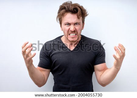 handsome caucasian man standing over isolated white background angry and mad raising fists frustrated and furious while shouting with anger. Rage and aggressive concept. Copy space. Close-up portrait Royalty-Free Stock Photo #2004055730