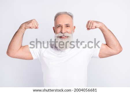 Portrait of positive grey hair beard old man show muscles wear white t-shirt isolated on grey color background Royalty-Free Stock Photo #2004056681