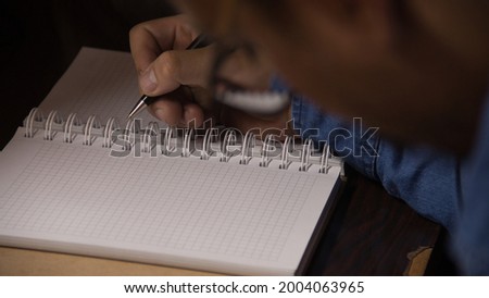 man hands with pen writes in notebook on wooden table