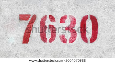 Red Number 7630 on the white wall. Spray paint. Number seven thousand six hundred thirty.