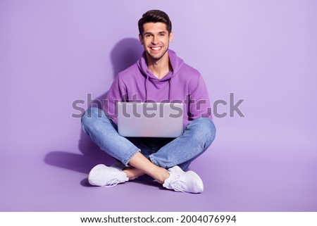 Portrait of attractive cheerful guy sitting lotus pose using laptop free time isolated over purple violet color background