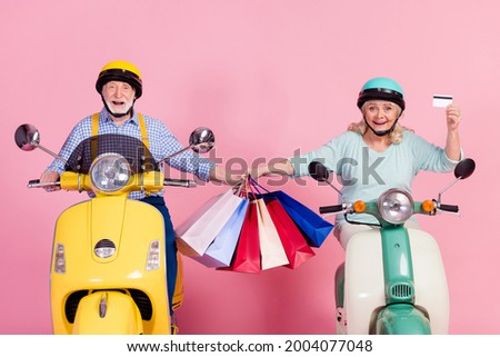 Photo of happy mature married couple ride drive moped after shopping hold credit card isolated on pink color background