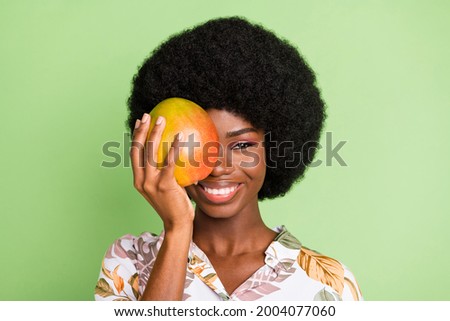 Photo of young attractive black girl happy positive smile close cover eye mango food tasty isolated over green color background