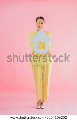 Portrait beautiful young asian business woman show home or house sign on color isolated background