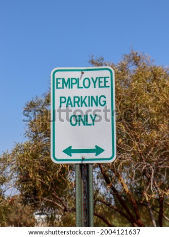 An Employee Parking Only sign with a bidirectional arrow below.