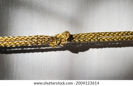 gold  rope knot isolated on a white background as a strong nautical marine line tied together as a symbol for trust and faith 