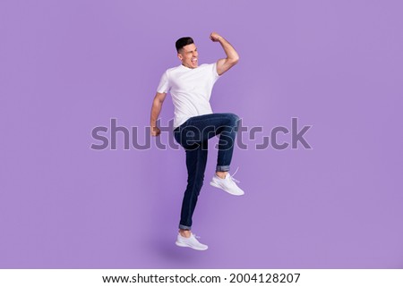 Full size photo of young cheerful crazy man jump up raise fist winner enjoy isolated on violet color background