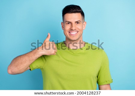 Photo portrait man in green t-shirt showing thumb up like gesture isolated pastel blue color background