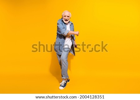 Full length body size of cool grandfather dancing feeling young in jeans jacket isolated on vivid yellow color background