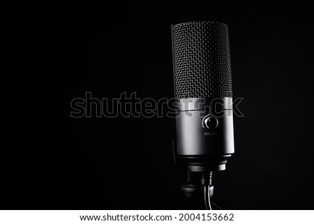 Studio microphone on dark background with copy space. Black professional condencer microphone. Podcast recording