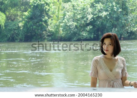 A short-haired Asian woman posing with a smiling river behind her.