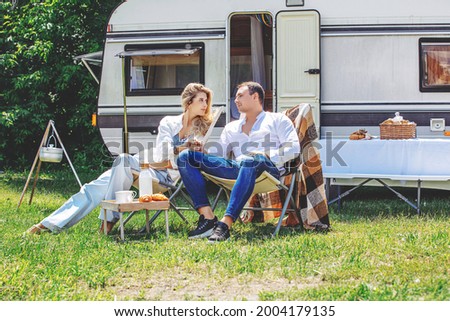Couple of a beautiful woman in love and a man in nature are relaxing traveling in a trailer, a mobile home Royalty-Free Stock Photo #2004179135