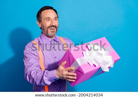 Profile side photo of mature man happy positive smile hold present box birthday isolated over blue color background