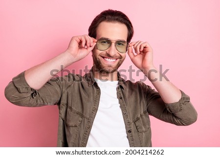 Photo of funny charming young guy dressed brown shirt smiling arms eyeglasses isolated pink color background