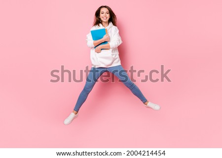Photo of adorable pretty young woman dressed white sweatshirt holding copybooks jumping high smiling isolated pink color background