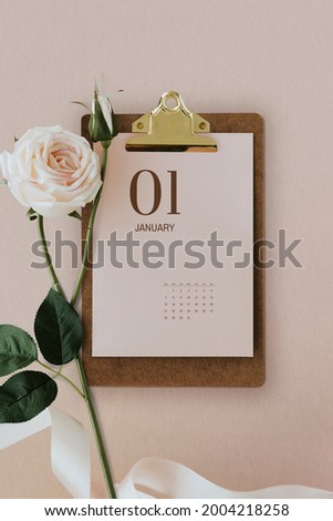 Pastel pink calendar on a cork clipboard with light pink rose