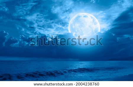 Night sky with moon in the clouds on the foreground blue sea "Elements of this image furnished by NASA