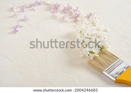 paint brush and lilac flowers on a light textured background copy space
