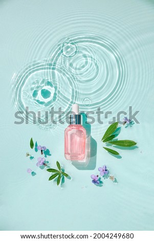 Moisturizing cosmetic products on water with drops. Serum glass bottle and cream jar on aqua surface with waves in sunlight. Concept for advertising organic moisturizing skin care, spa. Royalty-Free Stock Photo #2004249680