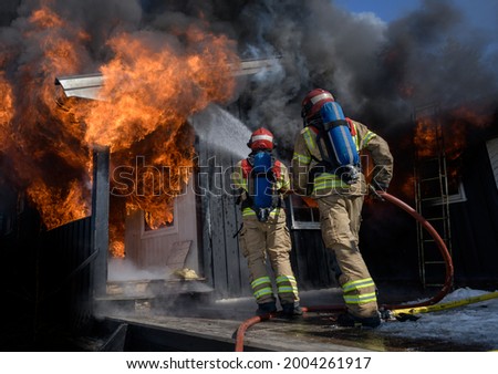 Firefighters trying to put out flames cabin on fire Royalty-Free Stock Photo #2004261917
