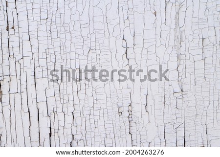 Textured wood surface covered with white, old, peeling paint and cracks. The rough finish is dirty, cracked and crumbling to a vintage look. The background and copy space. Royalty-Free Stock Photo #2004263276