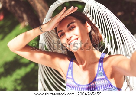 Beautiful woman sit on backyard chair at summer sunny day take photo selfie, excited cheerful happy